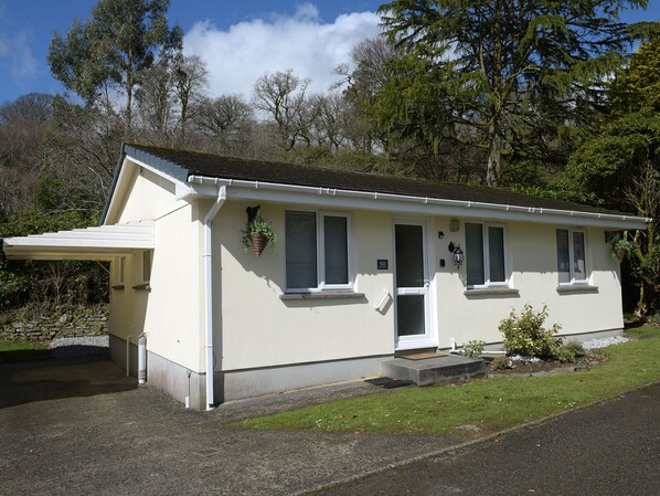 A single-story building with a flat roof, a covered porch, and a small front garden. - Little Retreat (Liskeard)