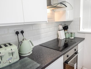 Enjoy cooking in this well-equipped kitchen with a stainless steel range hood, granite countertop, and ample counter space.
