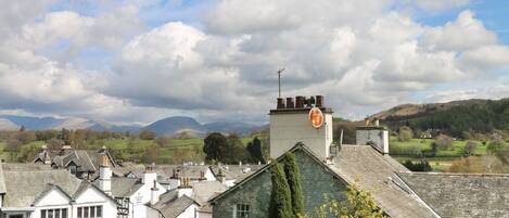 A traditional village with stone houses, a prominent church steeple, and a clear view of distant hills.