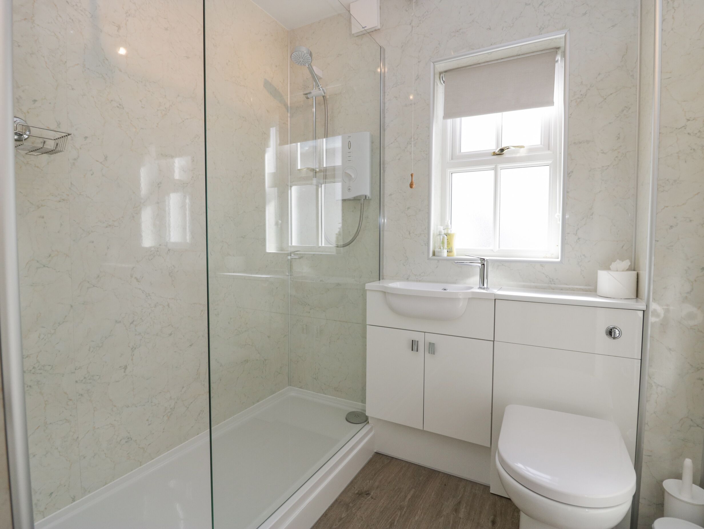 A modern bathroom with a glass-enclosed shower, a white sink, and a toilet.