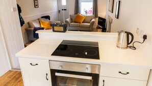 Una cocina compacta con una cocina por inducción Bosch, un horno empotrado y un hervidor.