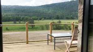 Een balkon met een houten vloer, een metalen tafel en een houten stoel.