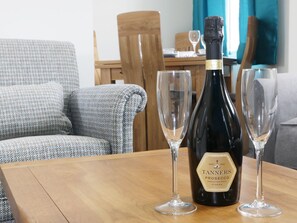 A bottle of Tannets Prosecco on a wooden table with two empty wine glasses beside it. - 7 Monkmoor Road (Shrewsbury)