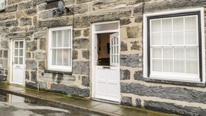 Ein Steinhaus mit mehreren Fenstern und Türen, einige davon mit Fensterläden.