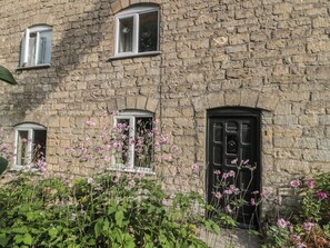 A stone building with three windows and a black door. - 1 Westcroft Cottage (Stonehouse)