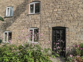 A stone building with three windows and a black door.