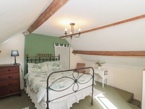 A bedroom with a bed, a dresser, a desk, a lamp, and a chandelier. - 1 Westcroft Cottage (Stonehouse)