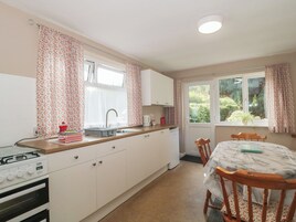 A compact kitchen with a gas stove, a sink, and a dining area with a table and chairs.