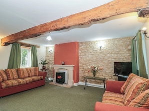 Una sala de estar con pared de piedra, chimenea, sofá y televisor.