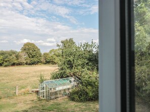 A greenhouse in a rural setting with a clear sky and surrounding vegetation.
