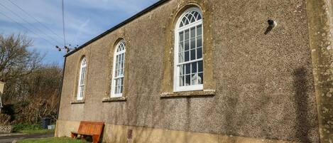 A building with three arched windows and a bench outside.