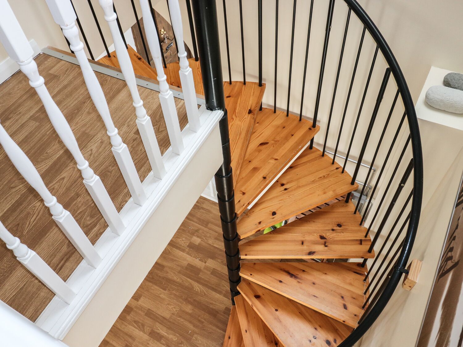 Un escalier en colimaçon avec des marches en bois et des balustrades blanches.