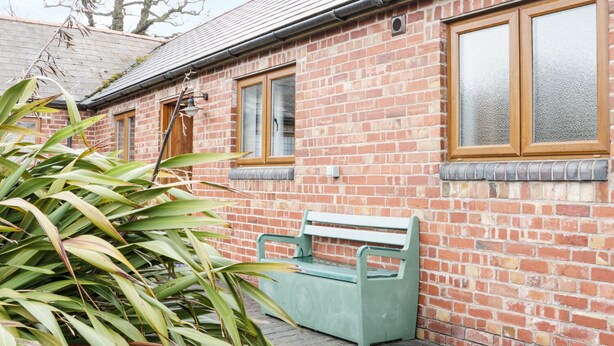 A brick building with a bench and a window. - Acorn Cottage 1 (Shrewsbury)