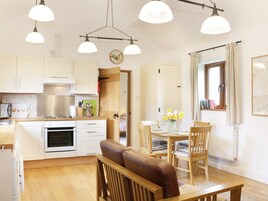 Una cocina acogedora con armarios de madera, un comedor con mesa y sillas, y una ventana con cortinas.