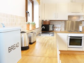 Una cocina con dispensador de pan, tostadora, hervidor y horno.
