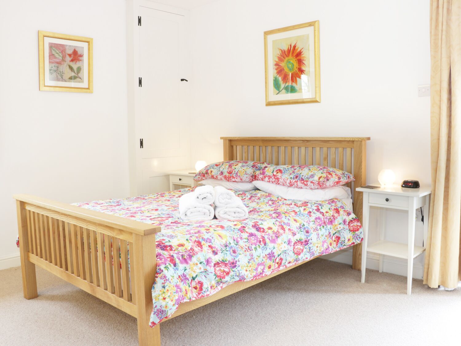 A neatly made bed with floral bedding, a wooden headboard, and two bedside tables with lamps.