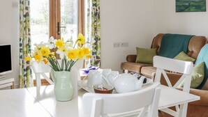 Ein Wohnzimmer mit einem für Tee gedeckten Esstisch, einer Couch und einem Bild an der Wand.