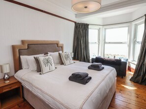 A hotel room with a large bed, a nightstand, a desk, and a view of the outdoors.