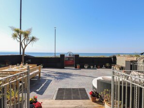 A patio with a view of the sea, outdoor seating, and potted plants. - Wavecrest (Pwllheli)