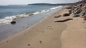 A beach with a rocky shoreline, clear sky, and calm sea. - Wavecrest (Pwllheli)