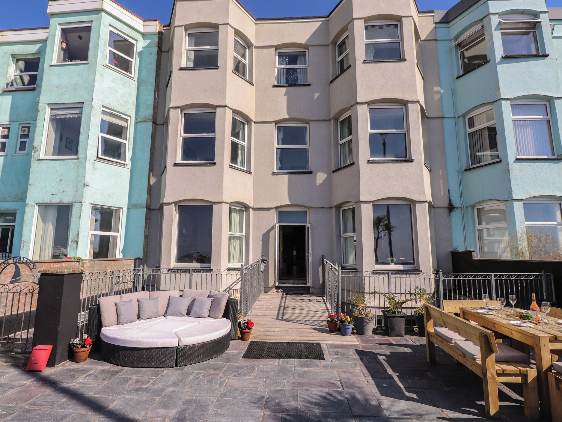 A multi-story residential building with a balcony, outdoor seating, and a dining area.