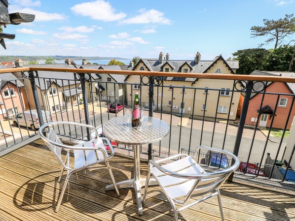 Enjoy a scenic view of the neighborhood from this balcony with a round table and two chairs.
