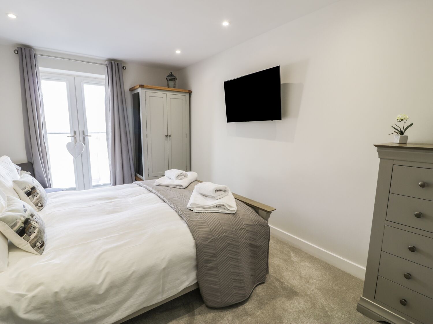 A bedroom with a bed, a dresser, a TV, and a wardrobe.