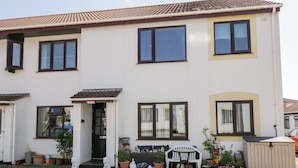 A two-story house with a front porch, potted plants, and a small garden. - Sea Breeze (Burnham-on-Sea)