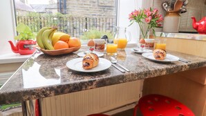 A kitchen counter with breakfast items, a red teapot, and a view of the outside. - Heather Corner (Keighley)