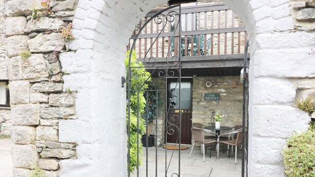 A stone archway leading to a building labeled "The Hayloft." - The Hayloft (Grange-over-Sands)