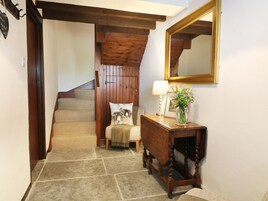 Una escalera con vigas de madera, una consola con lámpara y flores, y un espejo en la pared.