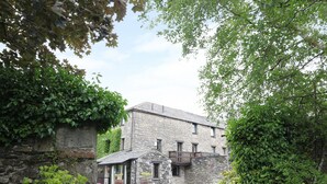 A stone building with a small porch and a paved entrance. - The Hayloft (Grange-over-Sands)