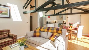 A cozy living room with a sofa, a coffee table, and a dining area with a table set for two.