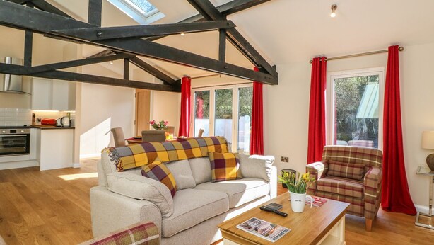 A spacious living area with a high ceiling, a sofa set, a coffee table, and a view of the outdoors.