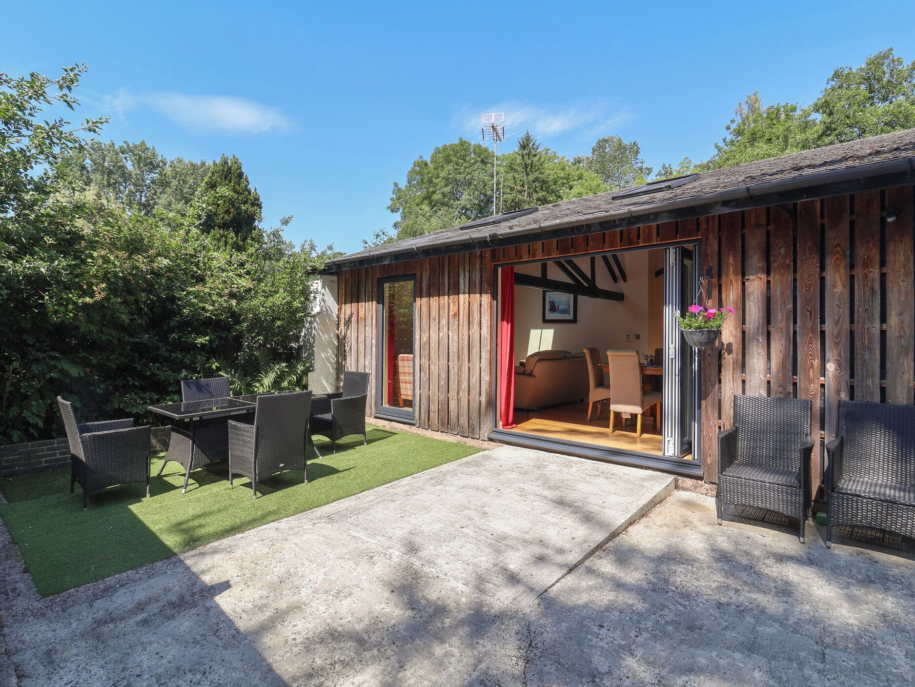 A wooden cabin with a patio area, outdoor furniture, and a view of the interior.