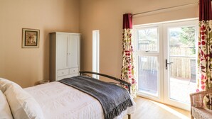 A bedroom with a bed, a wardrobe, a window with curtains, and a view of the outside.