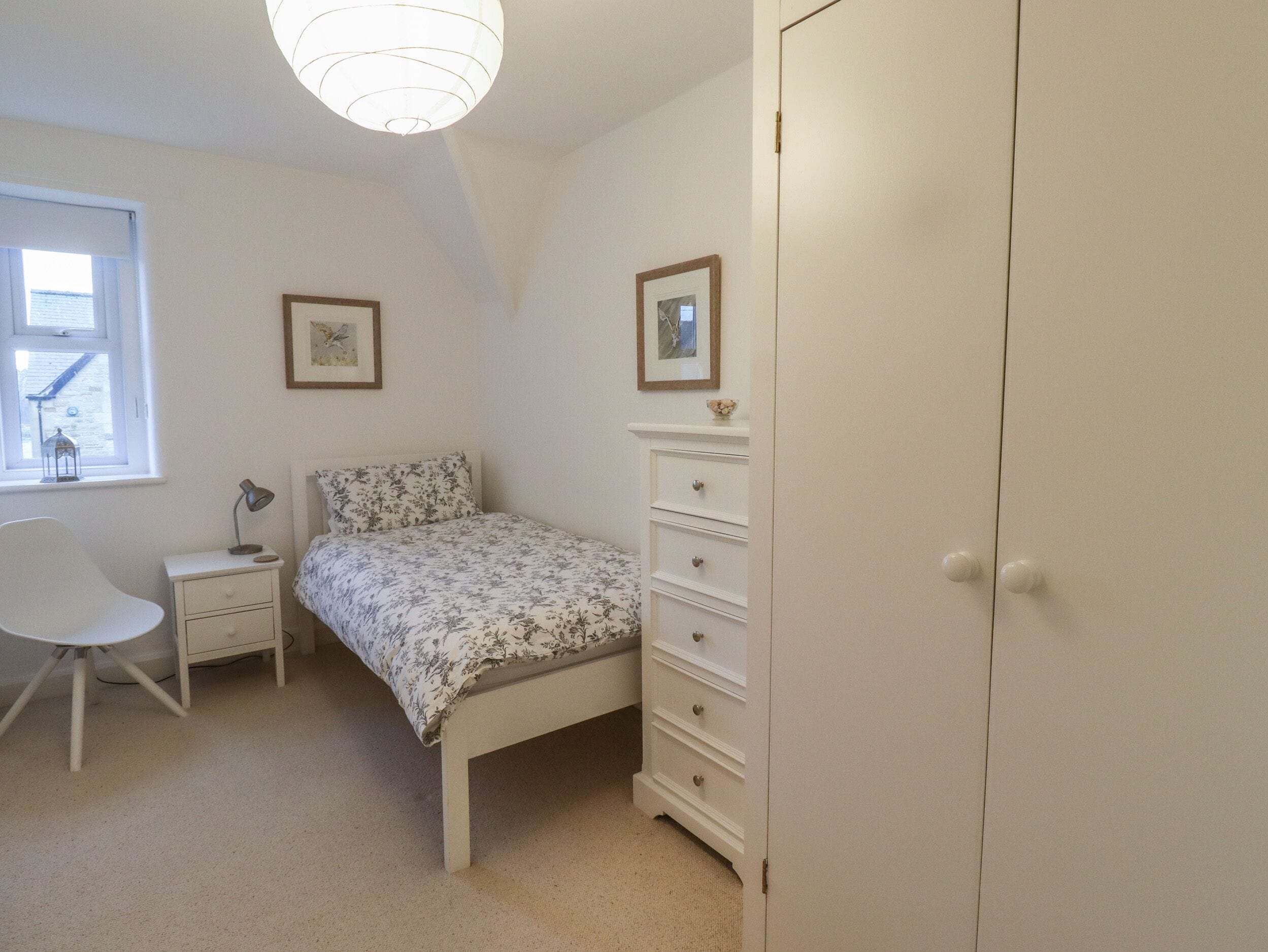 Un dormitorio con cama, mesita de noche, silla, cómoda y armario.