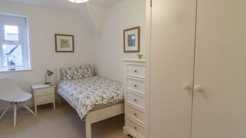 Un dormitorio con cama, mesita de noche, silla, cómoda y armario.