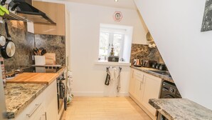 A kitchen with a stone countertop, wooden cabinets, a window, and a washing machine.