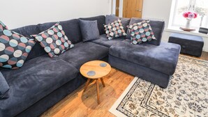 A modern living room with a dark grey sectional sofa, patterned throw pillows, a small wooden coffee table, and a patterned rug.