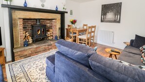 A living room with a fireplace, a sofa, a dining table with chairs, and a painting on the wall.