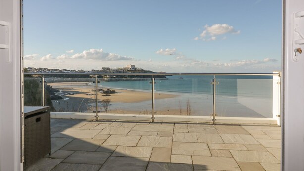 A balcony with a clear view of a beach and a distant castle. - Buena Vista (Newquay)