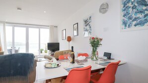 A modern living room with a sofa, a dining table with chairs, a TV, and artwork on the walls. - Buena Vista (Newquay)