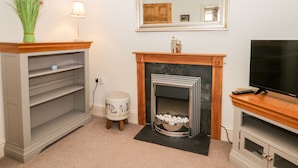 A living room with a fireplace, a television, a lamp, and a vase of flowers. - Spire View (Pickering)