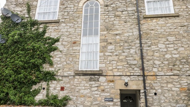 A stone building with two windows and a door, a sign reading "SPIRE VIEW", and satellite dishes on the roof. - Spire View (Pickering)
