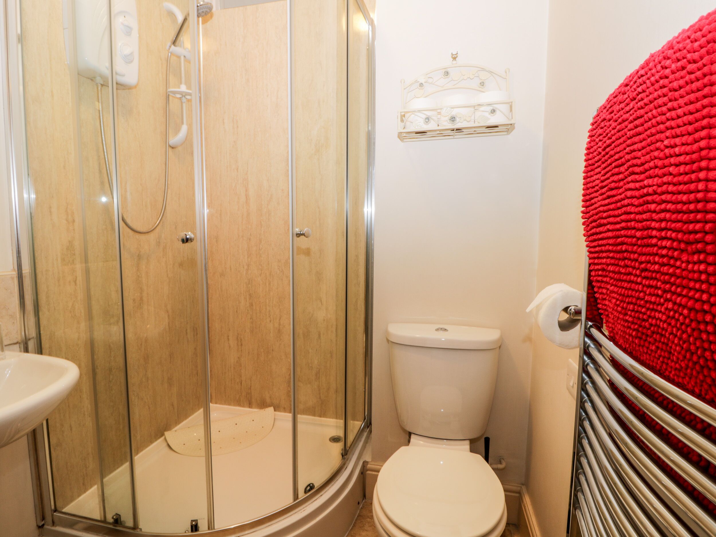 A bathroom with a glass-enclosed shower, a toilet, and a sink.