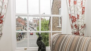 A room with a window overlooking a street, a sofa, and a statue of a dog. - Spire View (Pickering)