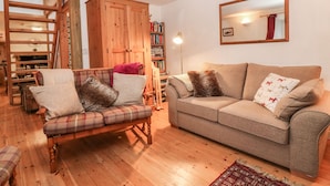 A cozy living room with a plaid sofa, a beige couch, and a wooden cabinet. - Creag Mhor Cottage (Kyle)