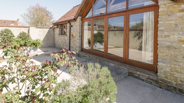 A stone building with a large glass door and a tiled roof. - The Stone Barn (Shepton Mallet)