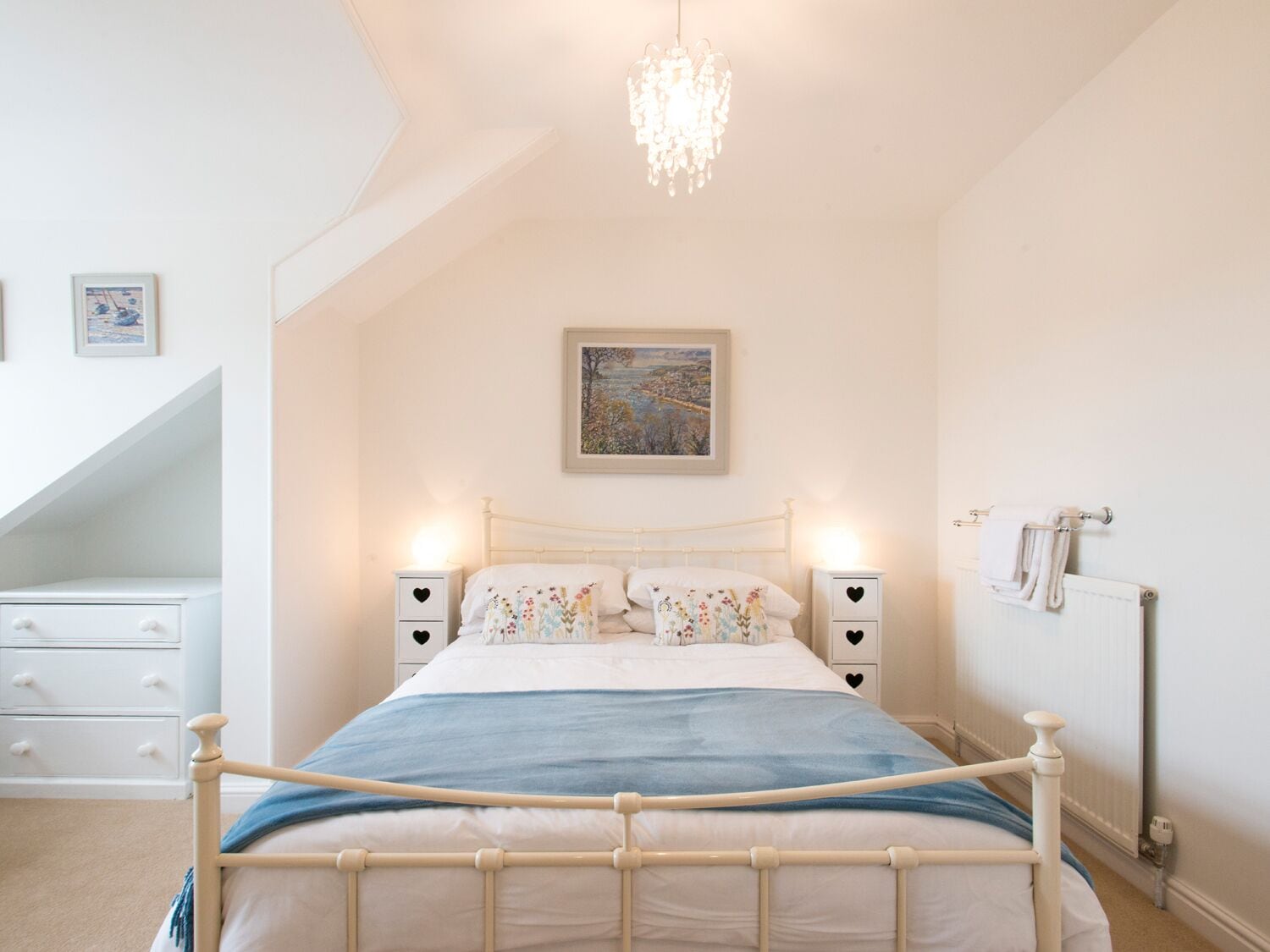 Quarto com cama, mesas de cabeceira, radiador e um candelabro.